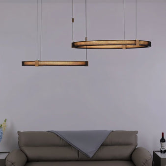 "Modern ring chandelier with perforated aluminum and acrylic diffusers, illuminating a contemporary living room with a sofa."