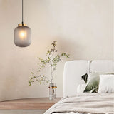 "Elegant pendant light made from glass and iron, hung above a side table in a cozy, contemporary bedroom setting."