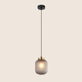 "Sleek pendant light with gray glass shade and gold accent, hanging in a minimalist style."
