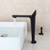 Black single-handle bathroom faucet with tall spout displayed next to white sink on marble countertop.