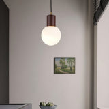 "Modern pendant light featuring sleek spherical design and wooden holder, ideal for dining rooms and kitchens."