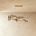 Modern chandelier with twisted wooden supports and cascading crystal discs, mounted on curved ceiling in contemporary interio