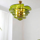 "A green Murano glass chandelier with layered petals, hanging in a room with white walls and a curtain."