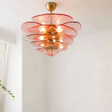 "A pink Murano glass chandelier with layered petals, hanging in a room with white walls and a plant."