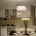 Modern kitchen featuring a pendant chandelier with a circular design, bright ambiance, elegant dining setup, and fresh flower