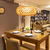 Stylish dining area featuring a round, amber chandelier above a wooden table set for dinner, creating a warm ambiance.