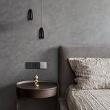 Pair of black Ailis Pendant Lights hanging beside a bed, adding modern ambient lighting to a stylish bedroom setting.