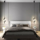 "Two black pendant lights with a spiral design, shown lit up on either side of a bed with gray bedding and a white headboard, in a room with gray walls and modern side tables."