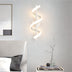 Modern spiral wall lamp in white finish, illuminating a stylish bedroom with soft light. Dimensions not specified.
