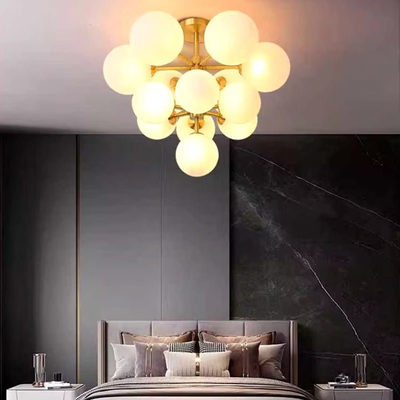 "A modern brass chandelier with frosted glass globes providing soft, ambient light in a contemporary bedroom."