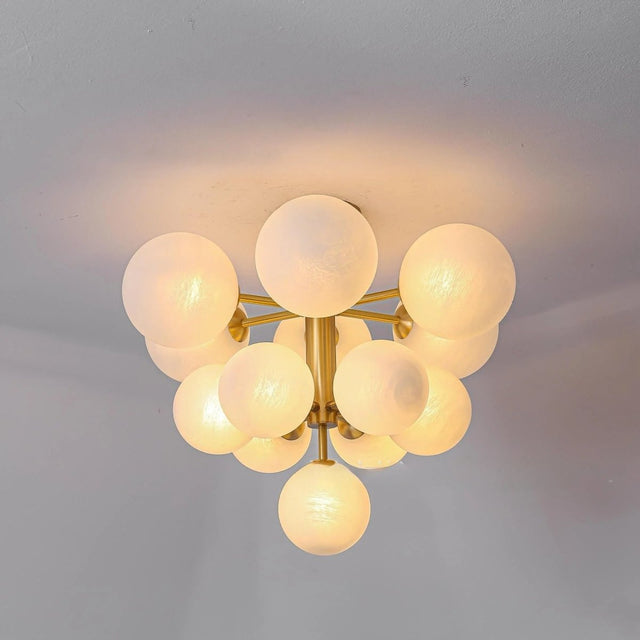 "A modern brass chandelier with frosted glass globes mounted on a ceiling, emitting a soft, ambient light."