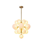 "A modern brass chandelier with frosted glass globes, isolated on a white background, showcasing its sculptural design."