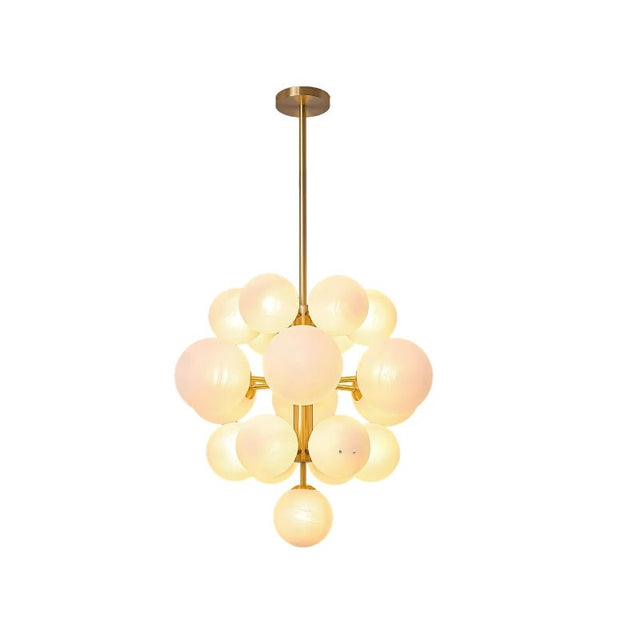 "A modern brass chandelier with frosted glass globes, isolated on a white background, showcasing its sculptural design."