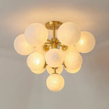 "A modern brass chandelier with frosted glass globes, isolated on a white background, showcasing its sculptural design."