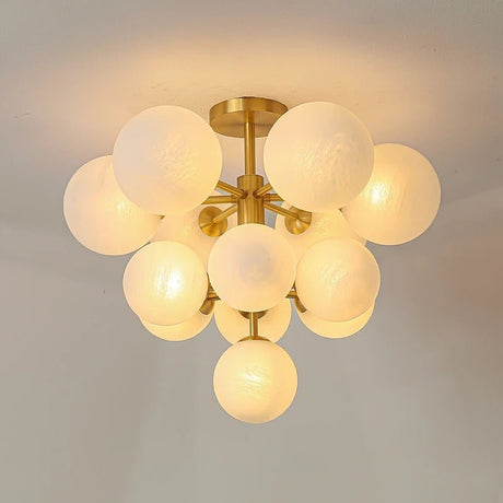 "A modern brass chandelier with frosted glass globes, isolated on a white background, showcasing its sculptural design."