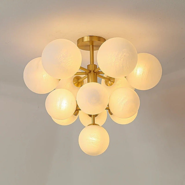 "A modern brass chandelier with frosted glass globes, isolated on a white background, showcasing its sculptural design."