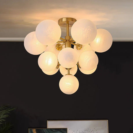 "A modern brass chandelier with frosted glass globes, featuring a sculptural design with multiple lights arranged around a central frame."