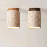 "Close-up of two cylindrical yellow travertine ceiling lights, one with light wood base and one with dark wood top, modern design."