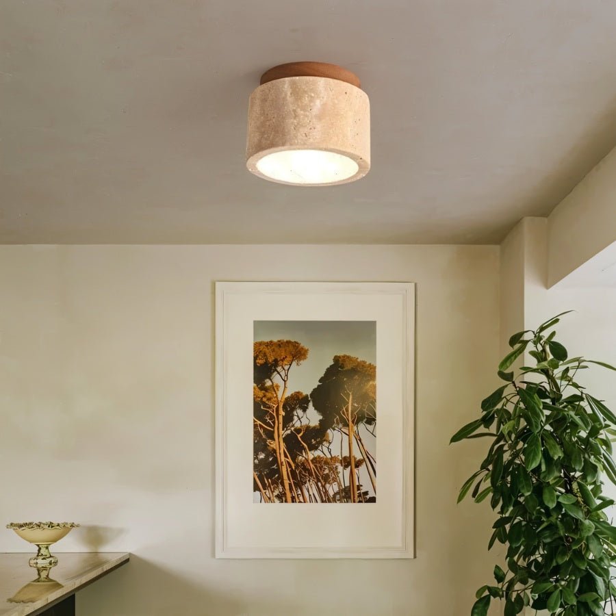 "Cylindrical yellow travertine ceiling light with light wood base in a room with artwork, modern interior lighting."