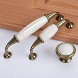 "Ceramic pull bar handles with a crackled glaze and zinc alloy supports, alongside a matching knob, in an antique brass finish."