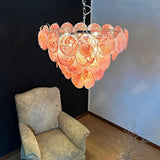 "A Murano glass disc chandelier in a room setting with a chair."