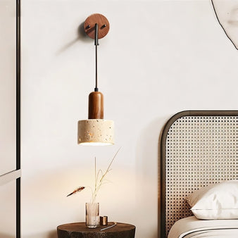 "A modern wall lamp with a cylindrical yellow travertine shade and a wooden mount, casting a soft, ambient light in a bedroom setting."