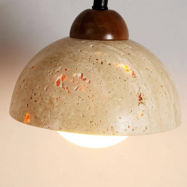 "Close-up of a modern wall lamp with a dome-shaped yellow travertine shade, showcasing the texture of the stone and the warm light it emits."