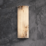 "Modern wall lamp crafted from cloud stone with a vertically grooved design, emitting a warm, diffused light."