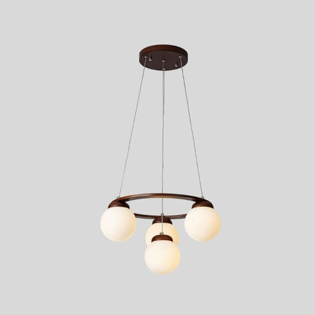 "Circular dark wood frame chandelier with four frosted glass globes, suspended by cables, isolated on a light gray background."