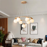 "Circular wood frame chandelier with frosted glass globes hanging above a sofa in a modern living room with artwork."