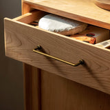 "A minimalist antique brass pull bar handle made of durable zinc, installed on a light wood drawer with an open drawer showcasing items inside."