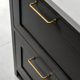 "Two minimalist antique brass pull bar handles made of durable zinc, installed on black drawers with a white countertop."