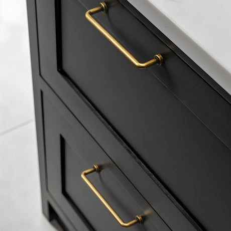 "Two minimalist antique brass pull bar handles made of durable zinc, installed on black drawers with a white countertop."