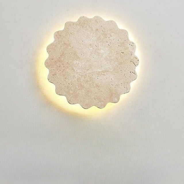 "Close-up of the Amon travertine wall lamp, showcasing its unique scalloped, flower-like design and the natural texture of the travertine stone, illuminated by a soft, warm glow."