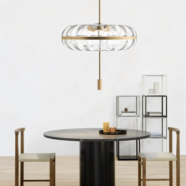 "Sculptural glass pendant light with rippled texture and metal frame, hanging above a dining table."