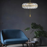"Sculptural glass pendant light with rippled texture and metal frame, hanging above a blue sofa and plant."
