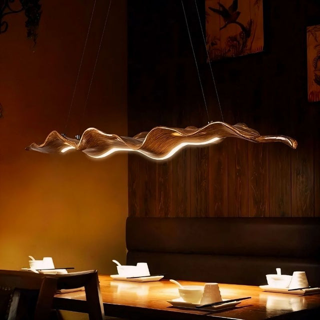 "Wave-inspired chandelier made from fiberglass and acrylic, suspended above a dining table, creating a modern, elegant ambiance with adjustable cables."