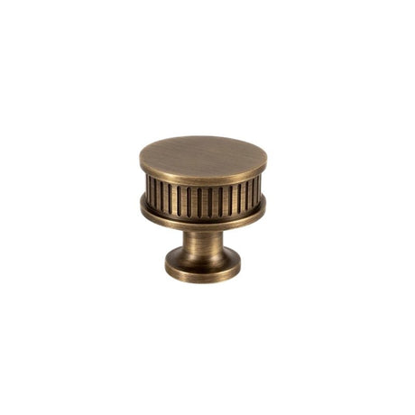 "An antique brass fluted cabinet knob with a ribbed texture and detailed design, isolated on a white background."
