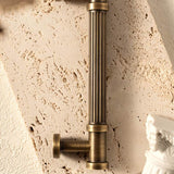 "Close-up of an antique brass fluted pull bar with detailed end caps on a textured background, highlighting its ribbed design and classical charm."