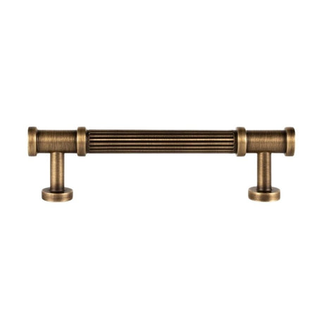 "An antique brass fluted pull bar with detailed end caps and a ribbed texture, isolated on a white background."