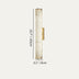 Cylindrical alabaster wall sconce with brass hardware and mounting bracket against neutral background.