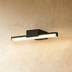 Black linear LED vanity light above circular mirror in modern bathroom with white sink.