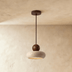 Pendant light with speckled gray shade, spherical accent, and chrome canopy on white background, front view.