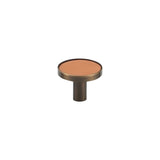 "A modern tan leather and brass cabinet knob on a white background."