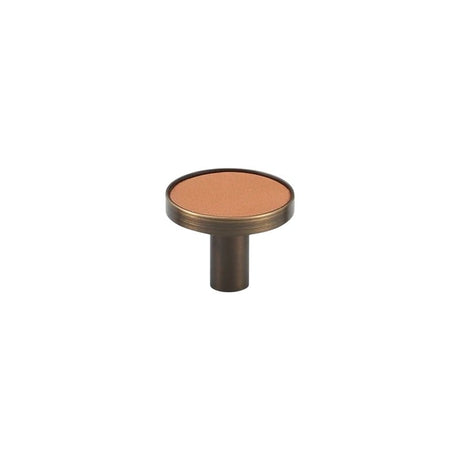 "A modern tan leather and brass cabinet knob on a white background."