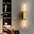 "A modern gold tube wall light on a gray wall in a living room."