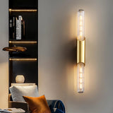 "A modern gold tube wall light on a gray wall in a living room."