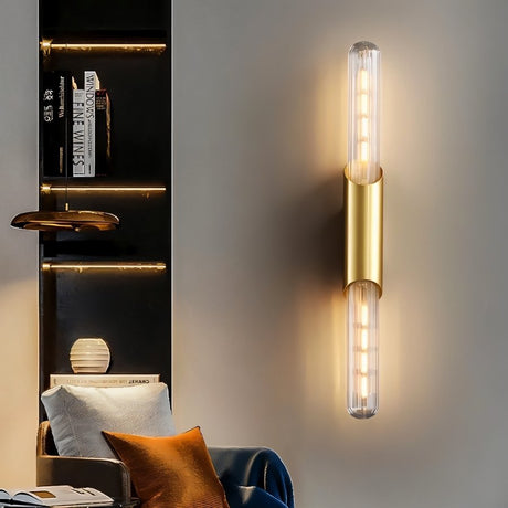 "A modern gold tube wall light on a gray wall in a living room."