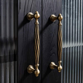 "Brass antique twisted fluted door pulls on a dark wood cabinet"