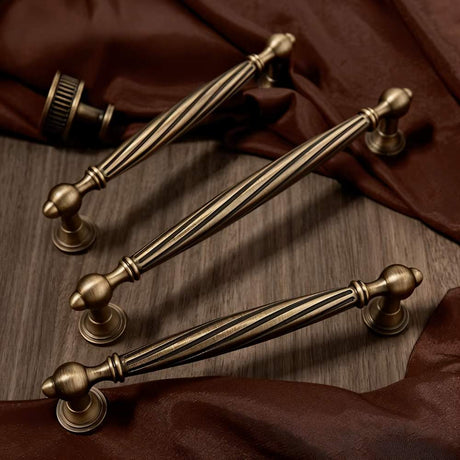 "Brass antique twisted fluted knobs and pulls on a wood background"